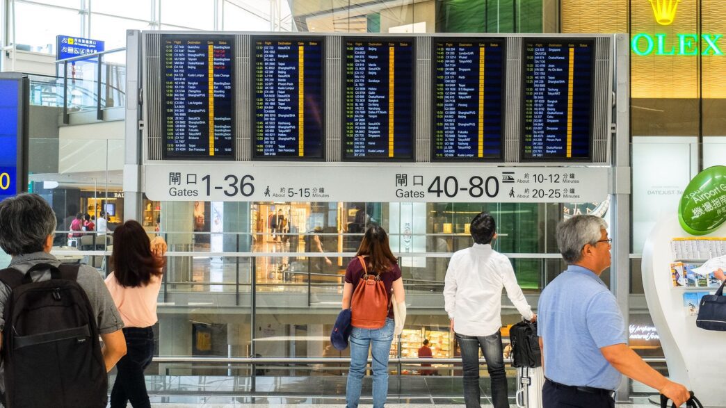 Traveler checking an airport departure board showing delayed flights