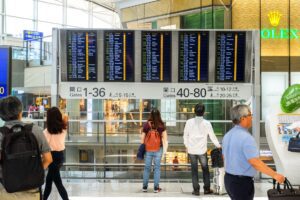 Traveler checking an airport departure board showing delayed flights