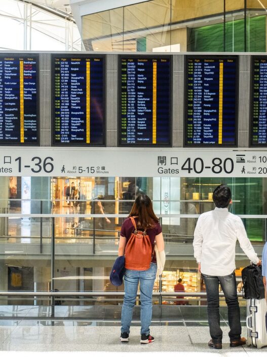 Traveler checking an airport departure board showing delayed flights