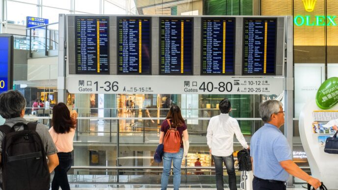 Traveler checking an airport departure board showing delayed flights