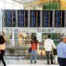 Traveler checking an airport departure board showing delayed flights