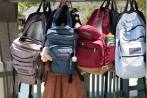 Parent and child shopping for back to school supplies with a backpack and notebooks