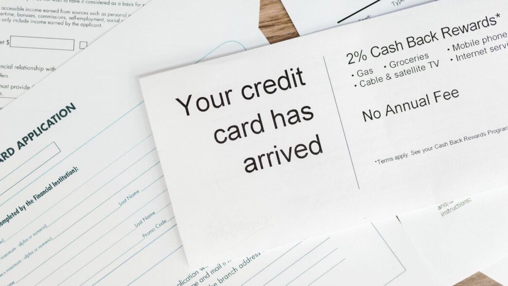 Credit cards and bills on a desk next to a calculator and budget notes