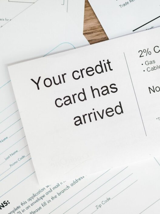 Credit cards and bills on a desk next to a calculator and budget notes