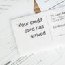 Credit cards and bills on a desk next to a calculator and budget notes
