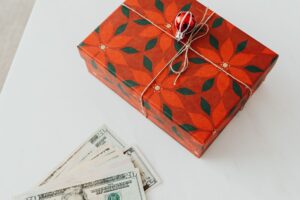 Wrapped holiday gifts beside cash and a savings envelope for a holiday sinking fund