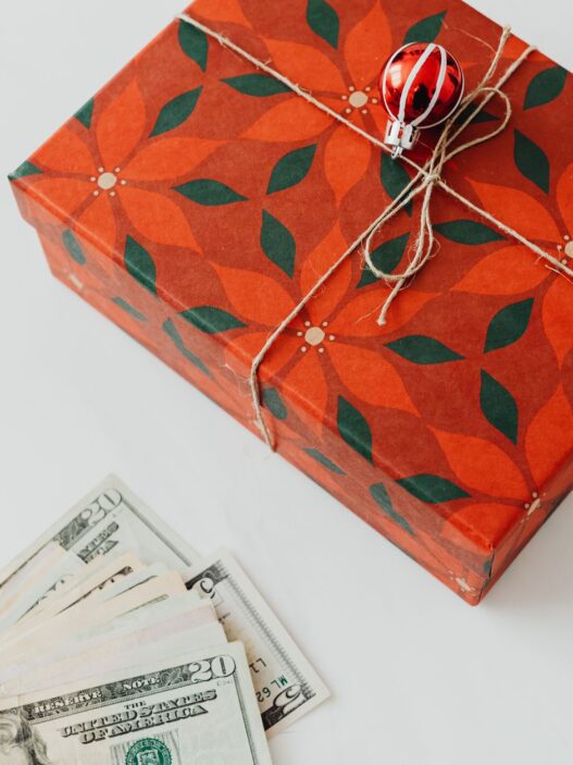 Wrapped holiday gifts beside cash and a savings envelope for a holiday sinking fund