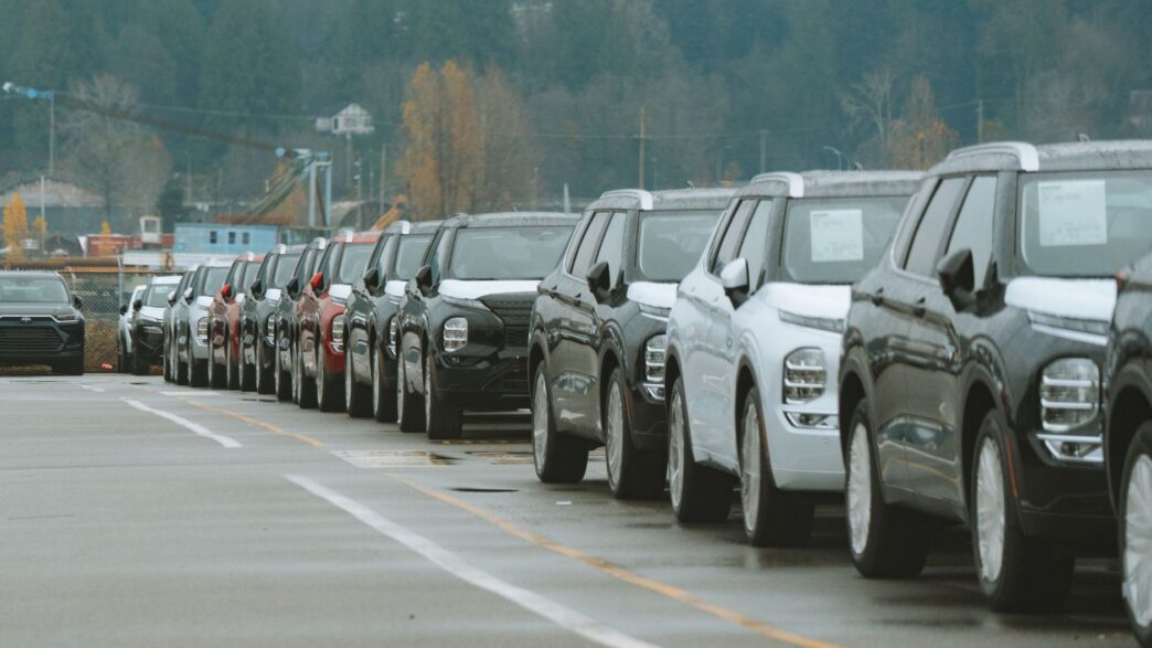 Rows of new vehicles on a car dealership lot during model-year clearance season