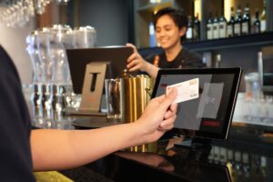 A customer paying at a restaurant counter with a card payment terminal