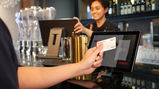 A customer paying at a restaurant counter with a card payment terminal