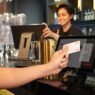 A customer paying at a restaurant counter with a card payment terminal