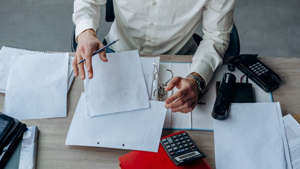 Worker reviewing employee benefits enrollment paperwork at a desk