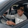 A young driver behind the wheel of a car, illustrating the cost of adding a teen driver to an auto policy