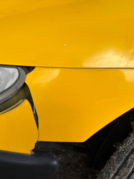 A damaged car bumper being inspected at a body shop, illustrating car insurance deductible costs