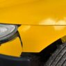 A damaged car bumper being inspected at a body shop, illustrating car insurance deductible costs