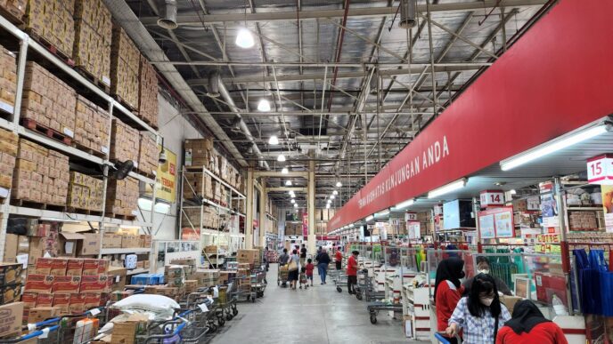 A shopping cart loaded with bulk groceries inside a warehouse club store