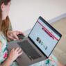 Person holding a credit card while shopping online on a laptop