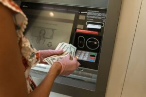 Hands counting cash bills next to a bank deposit counter