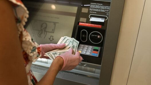 Hands counting cash bills next to a bank deposit counter