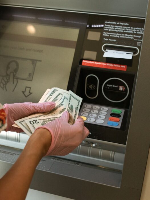 Hands counting cash bills next to a bank deposit counter
