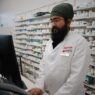 A pharmacist handling a prescription at the counter, illustrating formulary and tiering exception requests