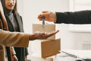 Renter holding apartment keys next to moving boxes in an empty apartment