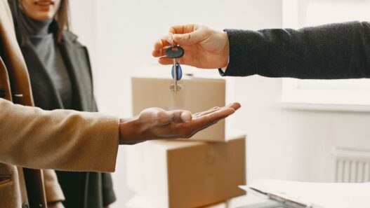 Renter holding apartment keys next to moving boxes in an empty apartment