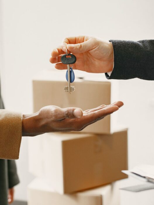 Renter holding apartment keys next to moving boxes in an empty apartment
