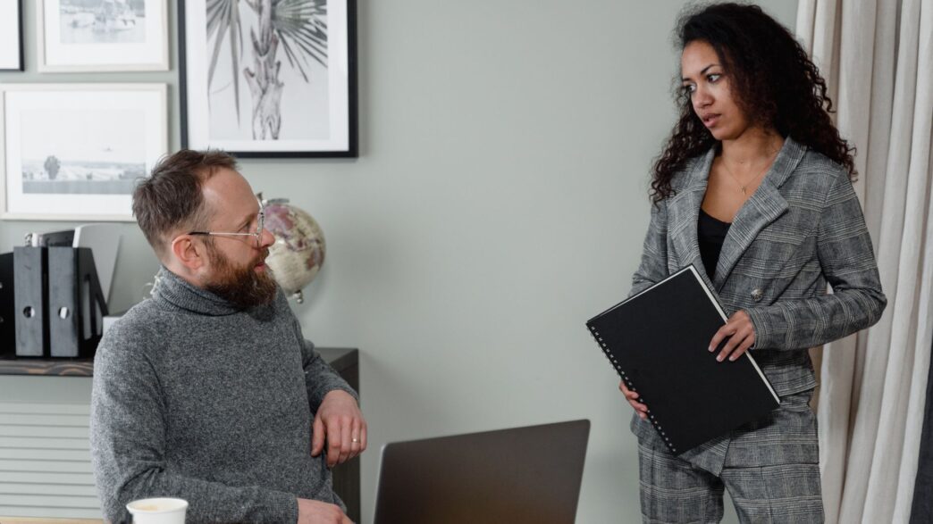 Two coworkers discussing pay at a desk during a salary planning meeting