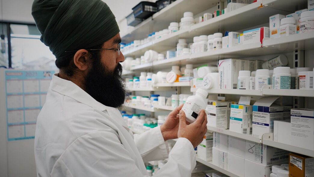Pharmacist handing prescription medication to a customer at a pharmacy counter