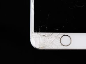 A smartphone with a cracked screen resting on a desk