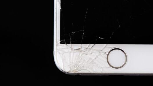 A smartphone with a cracked screen resting on a desk