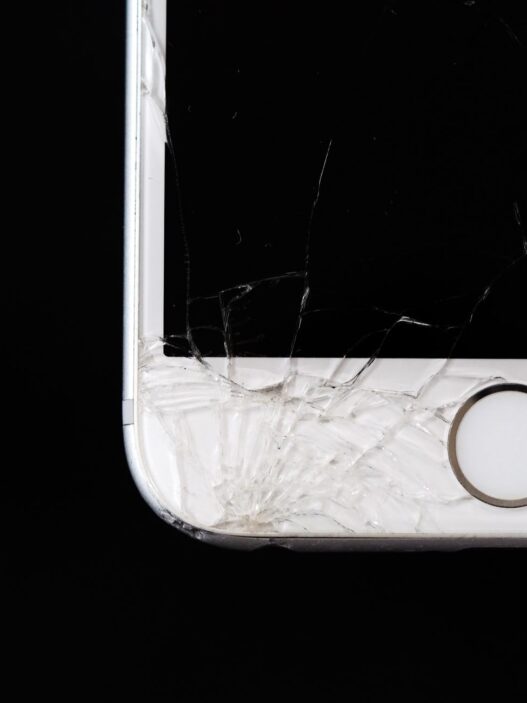 A smartphone with a cracked screen resting on a desk