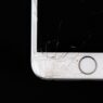 A smartphone with a cracked screen resting on a desk