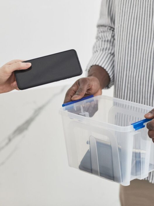 A person holding a smartphone next to a new phone box, illustrating carrier trade-in deals