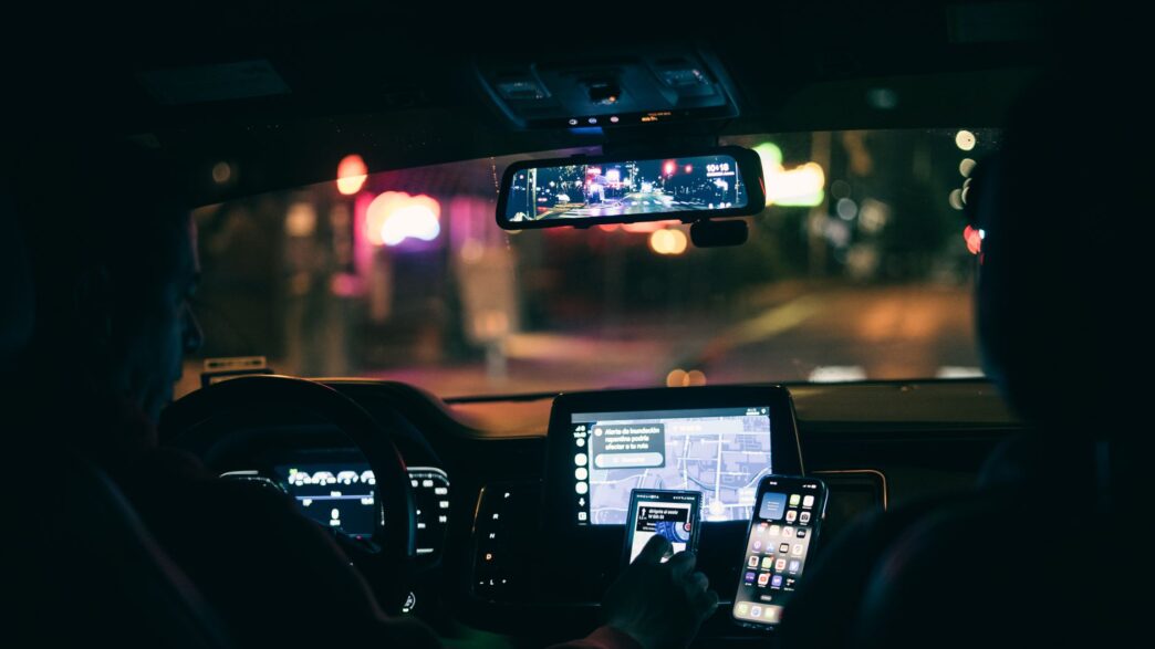 A driver using a rideshare app in a car, illustrating the rideshare insurance gap between coverage periods