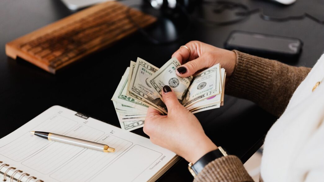 Hands counting cash dollar bills from a paycheck