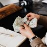 Hands counting cash dollar bills from a paycheck