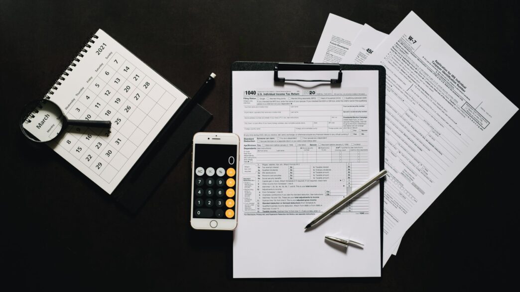 Federal tax return forms and a calculator on a desk before the October 15 extension deadline