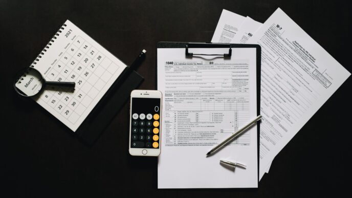 Federal tax return forms and a calculator on a desk before the October 15 extension deadline