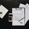 Federal tax return forms and a calculator on a desk before the October 15 extension deadline