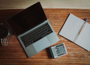 Person paying household bills online at a laptop next to a calculator