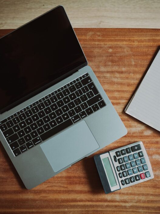 Person paying household bills online at a laptop next to a calculator