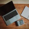 Person paying household bills online at a laptop next to a calculator