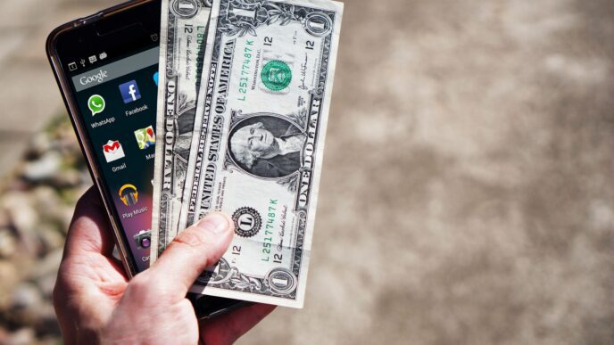 Hand holding cash and a smartphone, illustrating earned wage access pay apps and their fees