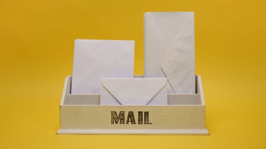 Stack of paper bills and envelopes on a table next to a calculator