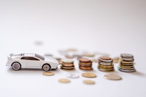 Piggy bank beside car keys, representing a sinking fund for paying car insurance in full
