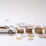 Piggy bank beside car keys, representing a sinking fund for paying car insurance in full
