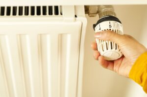 Hand turning a radiator valve, illustrating winter heating costs and utility budget billing